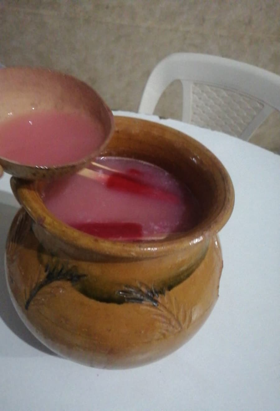 Chicha rosada servida con tutuma desde una jarra de barro